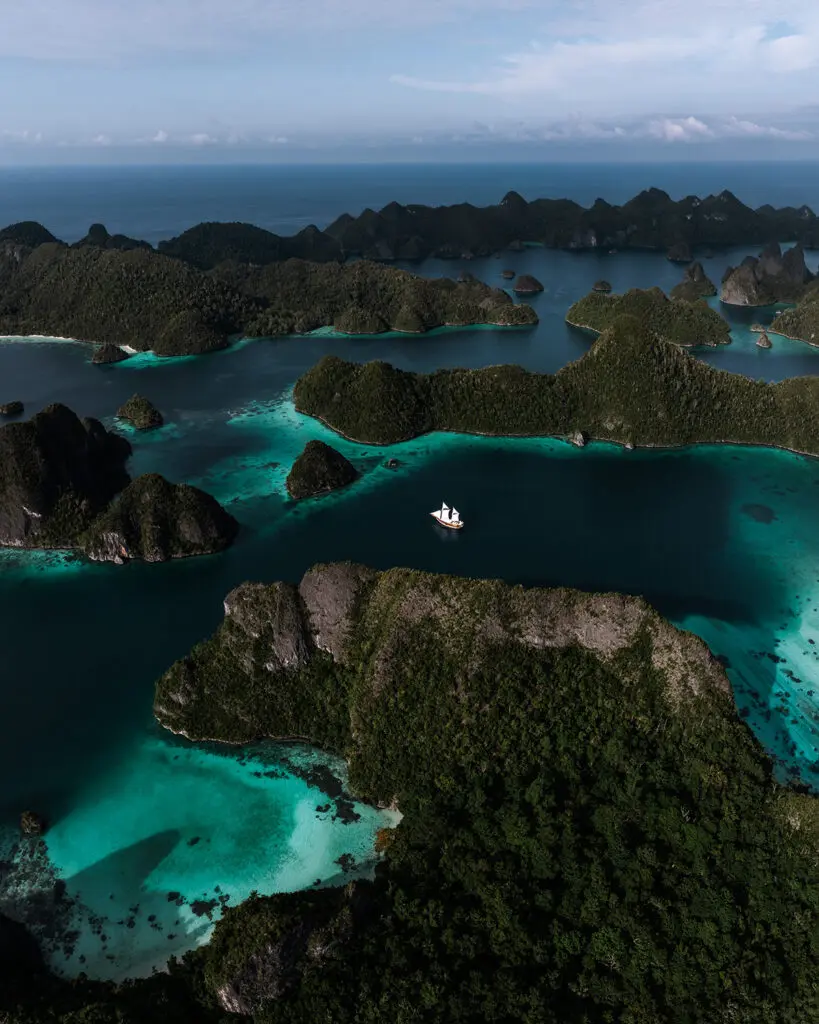 The Anne Bonny liveaboard yacht cruising between the dramatic limestone karst islands of Wayag, offering the ultimate luxury yacht experience in Raja Ampat.