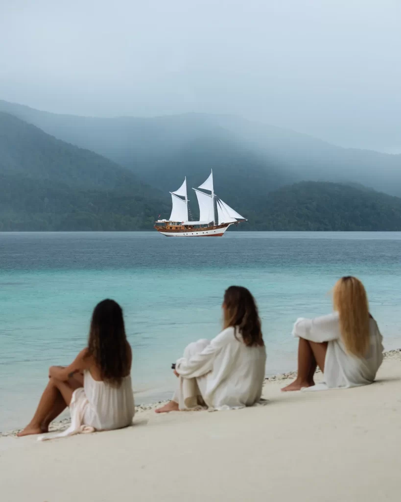 three woman on a beach in Raja Ampat enjoying the beautiful view of Anne Bonny liveaboard