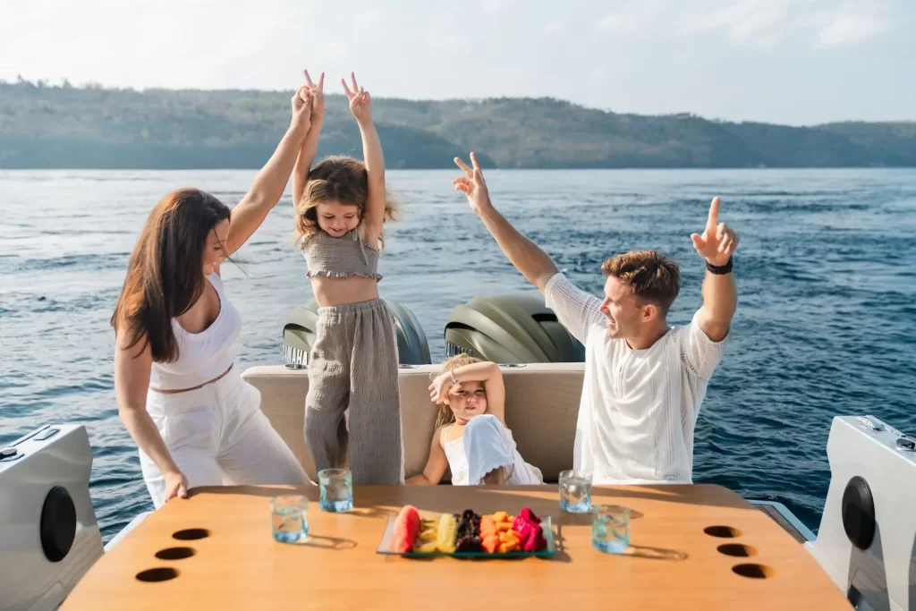a happy family siting by a dining table on the back of a luxury speed surrounded buy blue ocean.