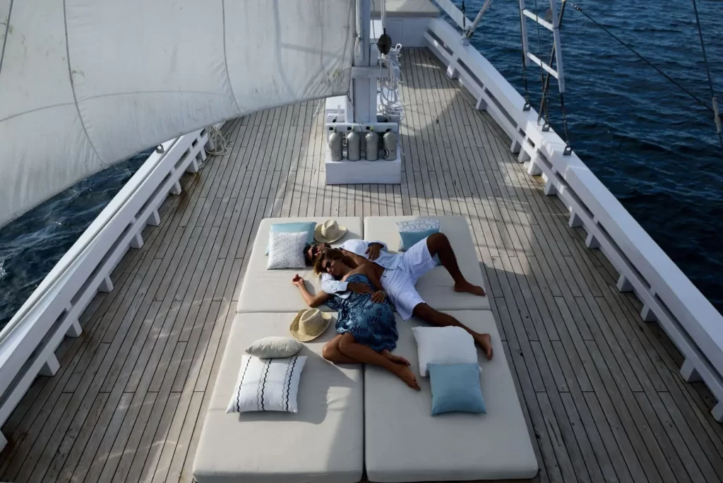 Honeymoon couple relaxing on the daybed of Alexa luxury Yacht in Komodo.