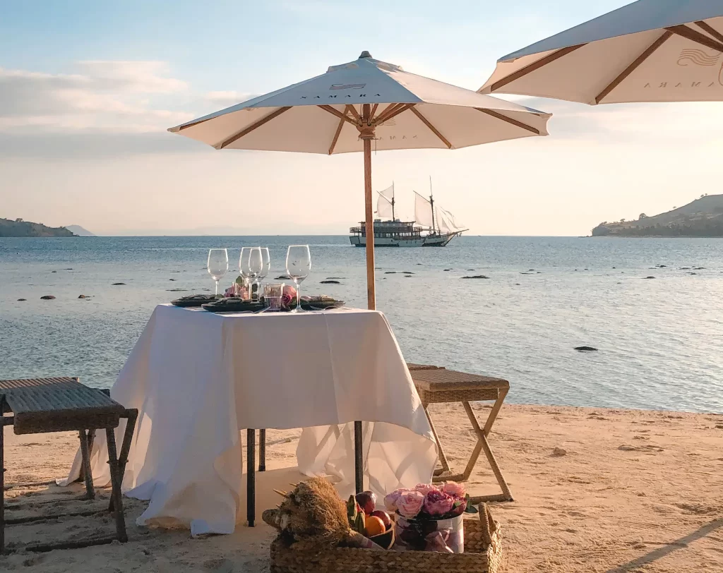 Beautifully laid out table for 2 on a private beach in Indonesia, with yacht Samara I in the background as the sunsets casting a beautiful light.
